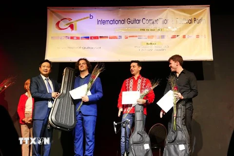 Giáo sư-nhạc sỹ Đặng Ngọc Long (bên trái) trao giải Nhất cho thí sinh đến từ Italy Luca Romanelli, giải Nhì cho thí sinh người Tây Ban Nha Samnuel Beluzan Rodriguez (áo đỏ) và thí sinh giải Ba đến từ Paraguay Raul Rolon. (Ảnh: Phương Hoa/TTXVN)