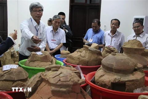 Các chuyên gia, nhà khoa học, đại biểu tham quan các di vật khảo cổ học. (Ảnh: Đinh Hương/TTXVN)