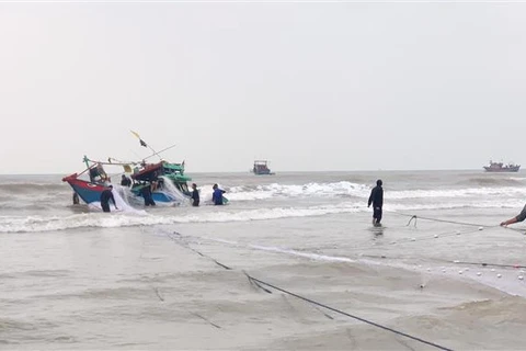 Bộ đội Biên phòng Quảng Bình phối hợp cùng với gia đình, chính quyền địa phương ứng cứu, hỗ trợ kéo thuyền bị nạn vào bờ. (Ảnh: TTXVN phát)