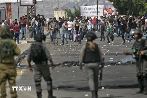Người Palestine và các lực lượng Israel trong cuộc đụng độ tại Nablus ngày 15/5/2022. (Ảnh: AFP/TTXVN)