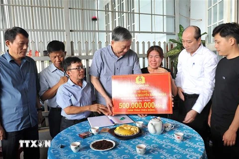 Bộ trưởng Bộ Công an Tô Lâm trao sổ tiết kiệm cho thân nhân liệt sỹ Nguyễn Đăng Nhân. (Ảnh: TTXVN phát)