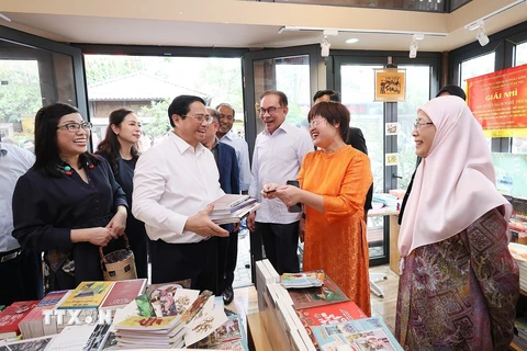 Thủ tướng Phạm Minh Chính mua sách tặng Thủ tướng Malaysia Anwar Ibrahim và Phu nhân. (Ảnh: Dương Giang/TTXVN)