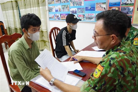 Lực lượng chức năng rà soát thông tin của các công dân vừa tiếp nhận từ lực lượng chức năng Campuchia. (Ảnh: Thanh Tân/TTXVN)