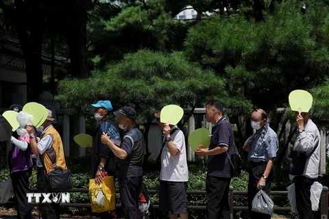Người dân xếp hàng nhận cơm từ thiện dưới trời nắng nóng tại Seoul, Hàn Quốc ngày 1/8/2023. (Ảnh: Yonhap/TTXVN)