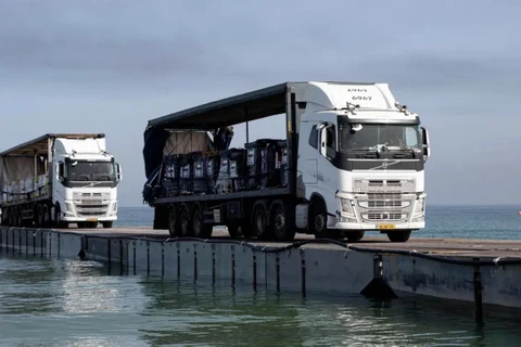 Đoàn xe tải chở hàng viện trợ nhân đạo di chuyển trên một cầu tàu do quân đội Mỹ lắp đặt ngoài khơi bờ biển Gaza (Ảnh: AP)