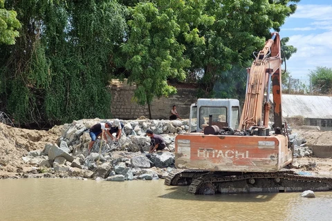 Đơn vị thi công gia cố đập bằng các rọ đá, đắp bao cát để dâng nước. (Ảnh: Nguyễn Thành/TTXVN)