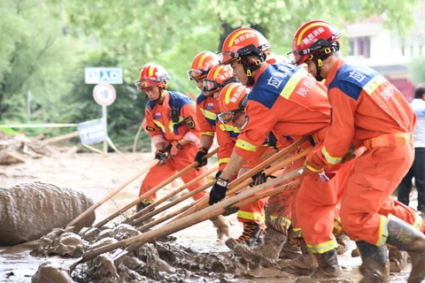 Lực lượng cứu hộ dọn bùn trên đường phố ở thành phố Bảo Kê, tỉnh Thiểm Tây, Trung Quốc sau mưa lớn, ngày 19/7/2024. (Ảnh: THX/TTXVN)