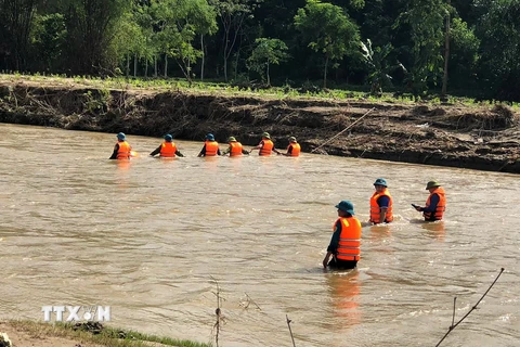 Huy động lực lượng tìm kiếm nạn nhân bị lũ cuốn. (Ảnh: TTXVN phát)