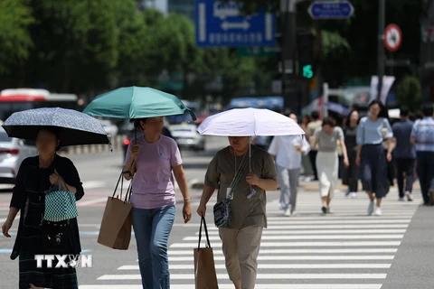 Người dân di chuyển trên đường phố dưới trời nắng nóng tại Seoul, Hàn Quốc, ngày 17/6/2024. (Ảnh: Yonhap/TTXVN)