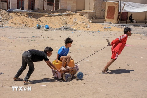 Trẻ em Palestine đi lấy nước sinh hoạt tại Khan Younis, Dải Gaza. (Ảnh: THX/TTXVN)