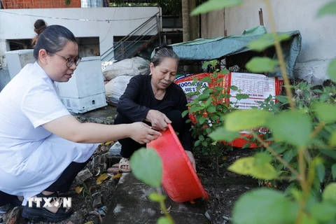 Nhân viên y tế xã Thượng Mỗ, huyện Đan Phượng, Hà Nội, hướng dẫn người dân xử lý nước thừa, nước đọng tại các vật dụng, đồ dùng sinh hoạt trong gia đình. (Ảnh: Minh Quyết/TTXVN)