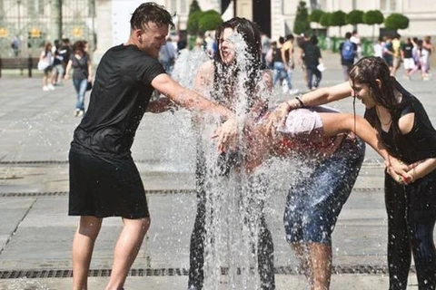Một số thanh niên ở Turin, miền Bắc Italy, tìm cách hạ nhiệt ở các vòi phun nước. (Nguồn: La Stampa) 