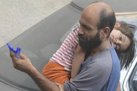 Bức ảnh anh Abdul ôm con gái Reem đi bán bút được đăng trên mạng. (Nguồn: edition.cnn.com) 