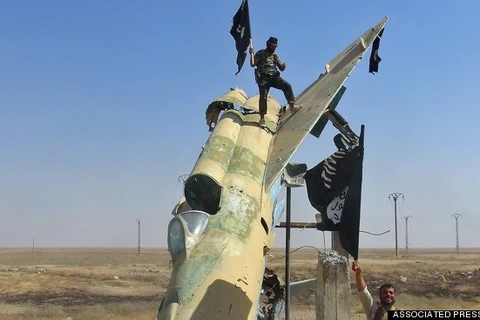 Phiến quân IS đứng trên một xác máy bay chiến đấu bị bắn rơi ở Iraq. (Nguồn: AP)