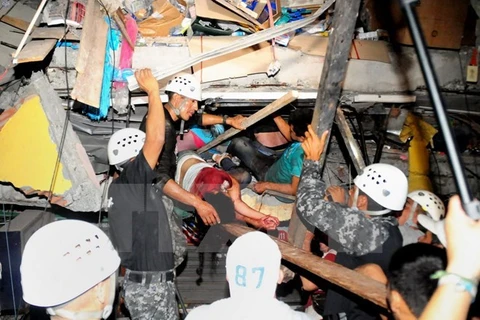 Lực lượng cứu hộ giải cứu người còn sống bị mắc kẹt trong một căn nhà đổ nát sau trận động đất. (Ảnh: AFP/TTXVN)