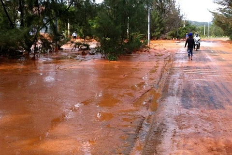 Sự cố vỡ bờ moong tại mỏ titan Suối Nhum khiến đất đỏ và bùn chảy tràn qua đường. (Ảnh: Nguyễn Thanh/TTXVN) 
