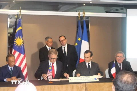 Tổng thống Pháp Francois Hollande và Bộ trưởng Công nghiệp và Ngoại thương Malaysia Mustapa Mohamed chứng kiến lễ ký kết các thỏa thuận hợp tác. (Ảnh: Hoàng Nhương/Vietnam+) 