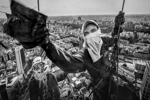 Đừng nhìn xuống! (Nguồn: NatGeo). Nhiếp ảnh gia Huỳnh Dũng đã chụp được bức ảnh về những nhân viên đang lau cửa kính ở độ cao tầng 60 tại Thành phố Hồ Chí Minh.