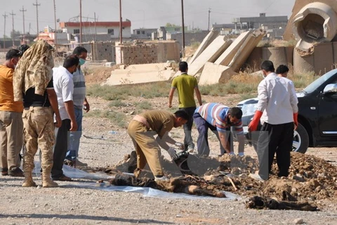 Người dân Iraq đưa xác các nạn nhân lên khỏi một hố chôn tập thể. (Nguồn: AFP/TTXVN)