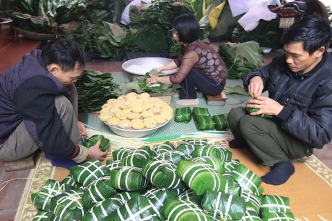 Các thành viên trong gia đình tham gia gói bánh chưng ở làng Tranh Khúc, huyện Thanh Trì, Hà Nội. (Ảnh: Vũ Sinh/TTXVN)