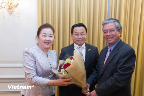 Đại sứ Phạm Quang Vinh (phải) tặng hoa chúc mừng Đại sứ Mai Sayavongs và phu nhân. (Ảnh: Đoan Hùng/Vietnam+)