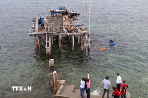 Khách tham quan vết tích nhà cao chân trên đảo chìm Đá Đông A. (Ảnh: Hữu Chiến/Vietnam+) 