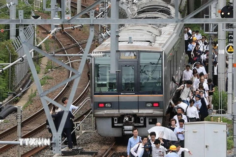 Hành khách sơ tán khỏi tàu hỏa sau trận động đất tại Osaka, Nhật Bản ngày 18/6. (Nguồn: AFP/TTXVN)