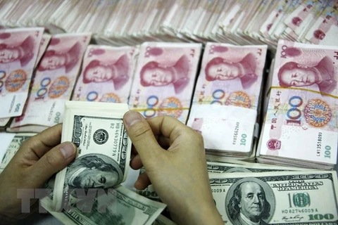 Đồng tiền giấy 100 USD (trên) và đồng 100 nhân dân tệ (phía dưới) tại một ngân hàng ở Hoài Bắc, tỉnh An Huy. (Nguồn: AFP/TTXVN)