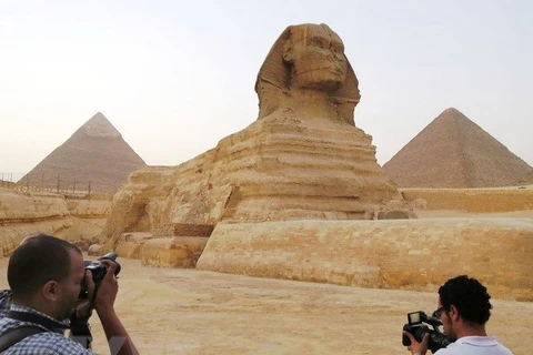 Du khách tham quan tượng Nhân sư bên cạnh kim tự tháp Menkaure (phải) và Khafre (trái) tại Giza, ngoại ô thủ đô Cairo. (Nguồn: Kyodo/TTXVN)
