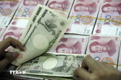 Đồng 10000 Yên Nhật (phía trên) và đồng 100 Nhân dân tệ của Trung Quốc (phía dưới) tại ngân hàng ở Hoài Bắc, tỉnh An Huy, Trung Quốc. (Ảnh: AFP/TTXVN)