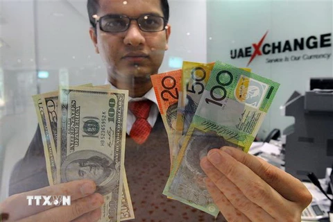 Đồng tiền đôla Australia (phải) và đồng đôla Mỹ tại quầy giao dịch tiền tệ ở Sydney, Australia. (Ảnh: AFP/ TTXVN)