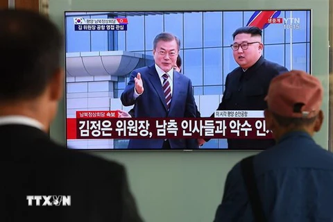 Người dân Hàn Quốc theo dõi hình ảnh truyền hình trực tiếp Nhà lãnh đạo Triều Tiên Kim Jong-un (phải, phía xa) đón Tổng thống Hàn Quốc Moon Jae-in (trái, phía xa) tại sân bay quốc tế Bình Nhưỡng ngày 18/9/2018. (Ảnh: AFP/ TTXVN)