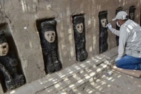 Một nhà khảo cổ làm việc bên những bức tượng gỗ được phát hiện ở Peru. (Nguồn: AFP)