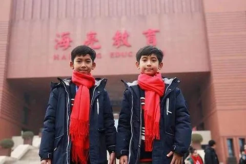 Thuch Salik (trái) đứng trước Trường Ngoại ngữ Hailiang ở tỉnh Chiết Giang, Trung Quốc. (Nguồn: Facebook/Thuch Salik)
