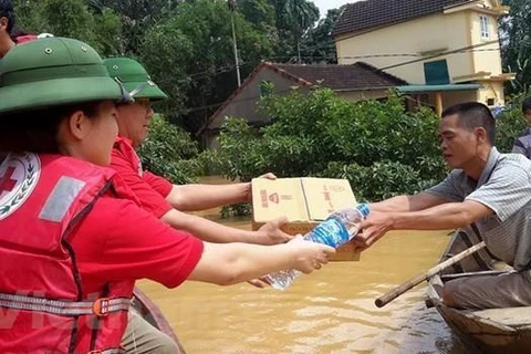 Cán bộ Hội Chữ thập Đỏ Việt Nam cứu trợ người dân vùng lũ. (Ảnh: PV/Vietnam+)