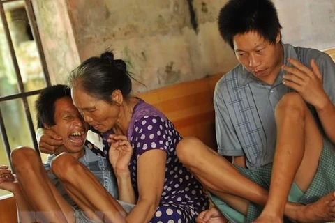 Bà Tạ Thị Chuyên chăm sóc cho con bị ảnh hưởng bởi chất độc da cam. (Ảnh: Minh Đức/TTXVN)