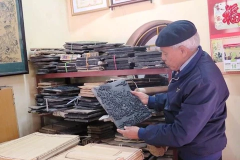 Nghệ nhân Nguyễn Đăng Chế giới thiệu bản khắc cổ của dòng tranh dân gian Đông Hồ. (Ảnh: TTXVN)
