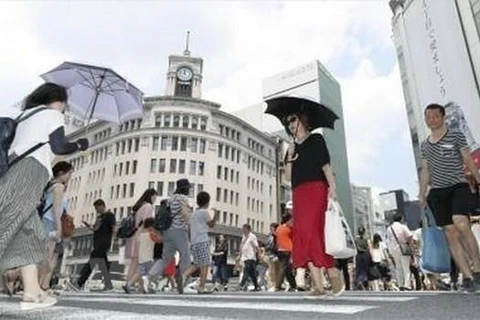 Người dân che ô tránh nắng tại Ginza, thủ đô Tokyo, Nhật Bản ngày 14/7. (Ảnh: Kyodo/TTXVN)