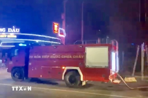 Lực lượng chức năng điều xe cứu hỏa đến hiện trường khống chế đám cháy không cho cháy lan sang cây xăng gần bên. (Ảnh: Nguyễn Văn Việt/TTXVN)