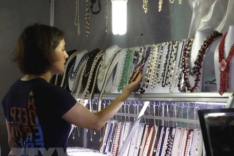 Du khách nước ngoài chọn mua sản phẩm thủ công mỹ nghệ tại chợ đêm Dinh Cậu, đảo Phú Quốc. (Ảnh: Hoàng Hải/TTXVN)