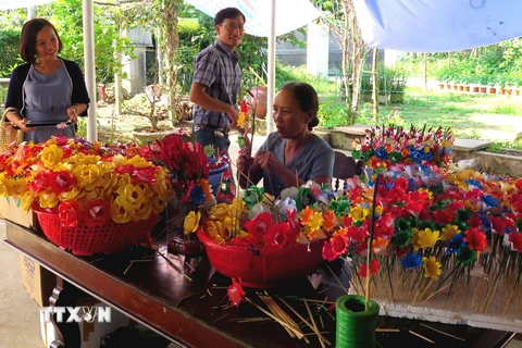 Nhiều du khách đến với làng nghề để tìm hiểu và trải nghiệm các công đoạn làm hoa. (Ảnh: Tường Vi/TTXVN)