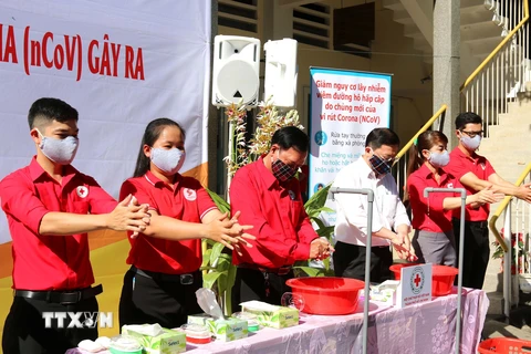 Các tình nguyện viên Hội Chữ Thập đỏ Việt Nam hướng dẫn người dân rửa tay bằng xà phòng sát trùng đúng cách. (Ảnh: Thanh Vũ/TTXVN)