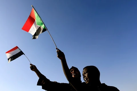 Người dân Sudan cầm quốc kỳ trong một cuộc tuần hành. (Nguồn: Reuters)