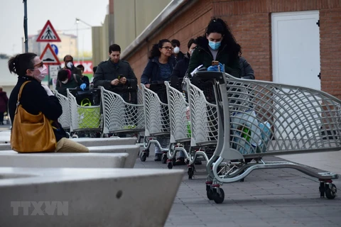 Người dân xếp hàng chờ đợi bên ngoài một siêu thị ở Bologna, Italy ngày 20/3/2020, trong bối cảnh dịch COVID-19 lan rộng. (Ảnh: THX/TTXVN) 