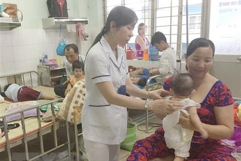 Bác sỹ khoa Nhi thăm khám cho trẻ mắc tay chân miệng. (Ảnh: Nam Thái/TTXVN)