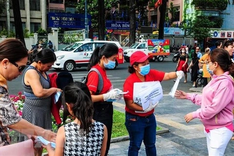 Nhân viên Sở Du lịch Thành phố Hồ Chí Minh phát khẩu trang miễn phí cho khách du lịch. (Ảnh: Đinh Hằng/TTXVN)
