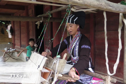 Người phụ nữ Lự tận dung thời gian rảnh rỗi để dệt những bộ quần áo cho gia đình. (Ảnh: Việt Hoàng/TTXVN)