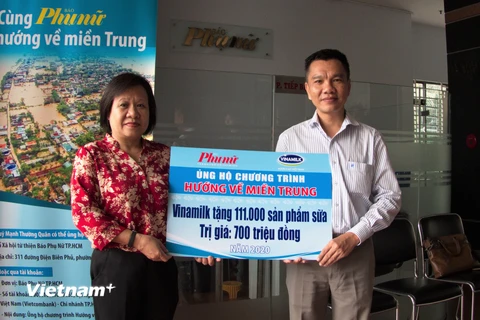 Ông Nguyễn Trung, Chủ tịch Công đoàn Công ty Vinamilk đại diện tập thể người lao động của công ty trao bảng tượng trưng 111.000 sản phẩm dinh dưỡng ủng hộ đồng bào miền Trung. (Nguồn: Vietnam+)