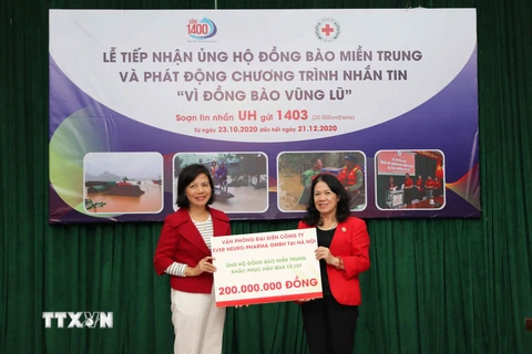 Chủ tịch Hội Chữ thập Đỏ Việt Nam Nguyễn Thị Xuân Thu tiếp nhận ủng hộ đồng bào miền Trung từ các cơ quan, tổ chức và doanh nghiệp. (Ảnh: Thanh Tùng/TTXVN)