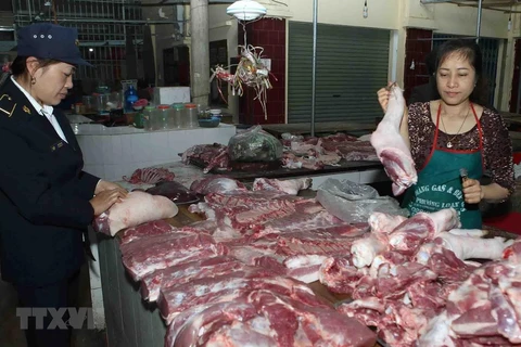 Nhân viên Thú y kiểm tra sản phẩm thịt lợn tại hộ kinh doanh trong chợ. (Ảnh: Vũ Sinh/TTXVN)